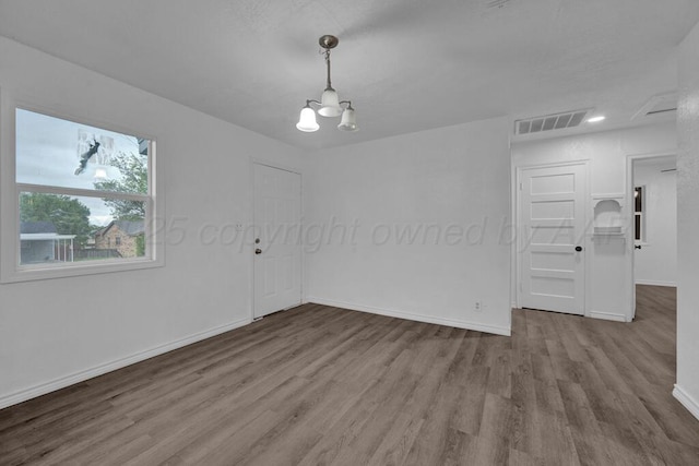 301 Estireno St, Borger, TX 79007 - empty room featuring an inviting chandelier, visible vents, wood finished floors, and baseboards