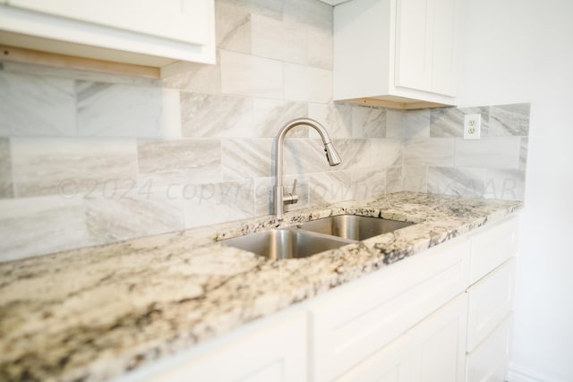 kitchen featuring white cabinets, tasteful backsplash, light stone counters, and sink