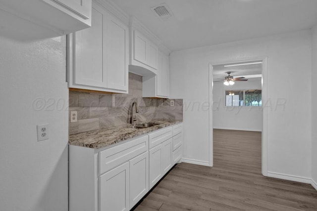 301 Estireno St, Borger, TX 79007 - kitchen featuring light stone counters, visible vents, a sink, decorative backsplash, and white cabinets
