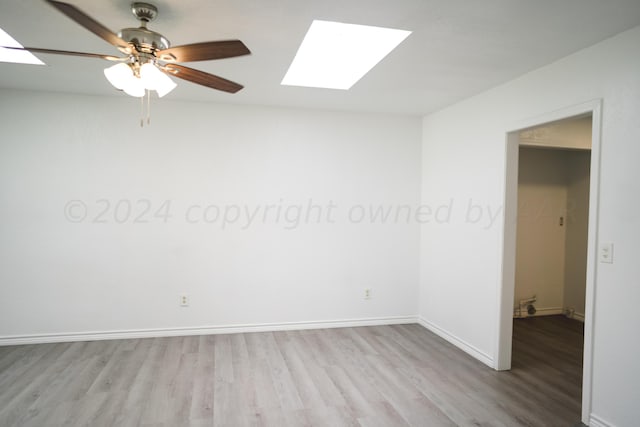 empty room featuring ceiling fan, light hardwood / wood-style flooring, and a skylight