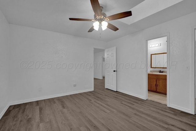 301 Estireno St, Borger, TX 79007 - unfurnished bedroom with a sink, connected bathroom, baseboards, and wood finished floors