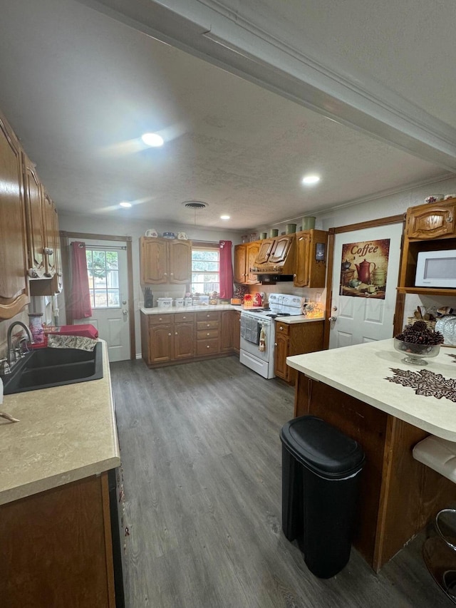 kitchen with white appliances, dark wood-style floors, brown cabinets, light countertops, and a sink