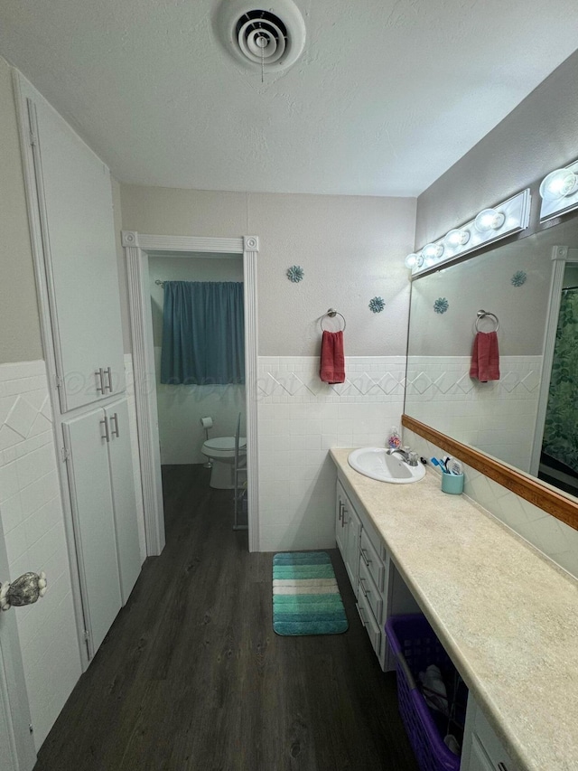 bathroom featuring tile walls, visible vents, a textured ceiling, vanity, and wood finished floors