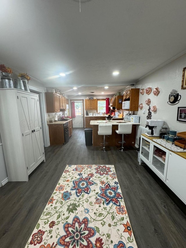 kitchen featuring dark wood-style flooring, light countertops, a peninsula, and a breakfast bar area