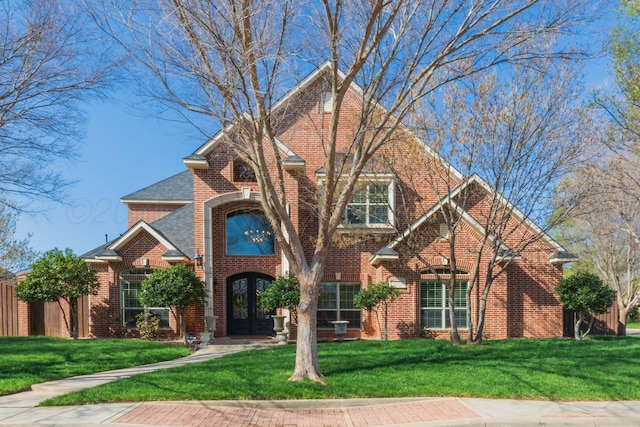 traditional home featuring brick siding, french doors, and a front lawn