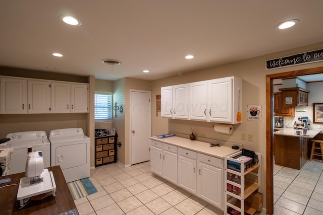 kitchen with washing machine and dryer, white cabinetry, and light tile patterned floors