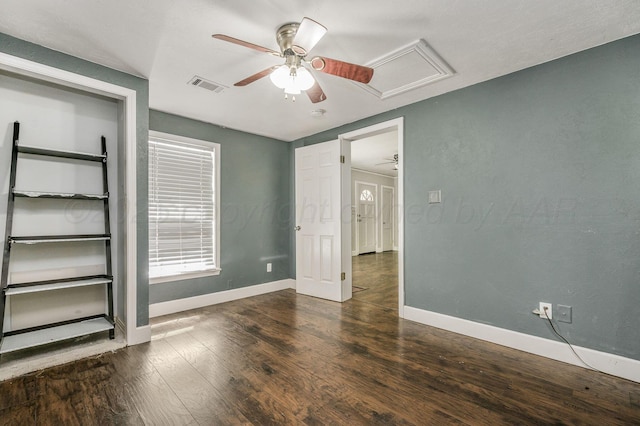 unfurnished bedroom with visible vents, attic access, baseboards, and wood finished floors