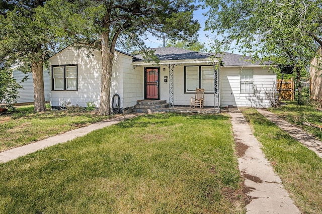 ranch-style house with roof with shingles, fence, and a front yard