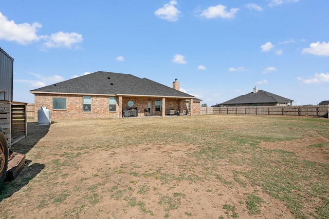 3851 Whitetail Springs Rd, Amarillo, TX 79119 - rear view of house with a chimney, a fenced backyard, a yard, and brick siding