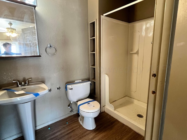 bathroom featuring wood-type flooring, toilet, sink, and a shower