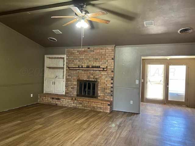 unfurnished living room featuring hardwood / wood-style flooring, crown molding, a brick fireplace, and ceiling fan