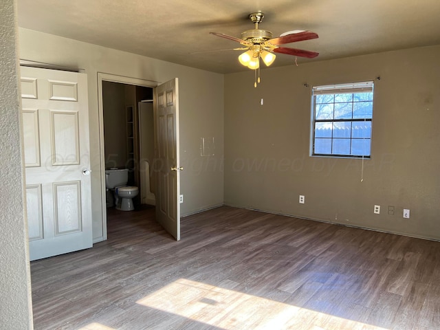 unfurnished bedroom featuring ceiling fan, wood-type flooring, and connected bathroom