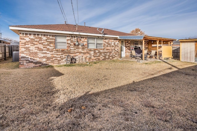 rear view of house featuring a patio, central AC unit, fence, and brick siding