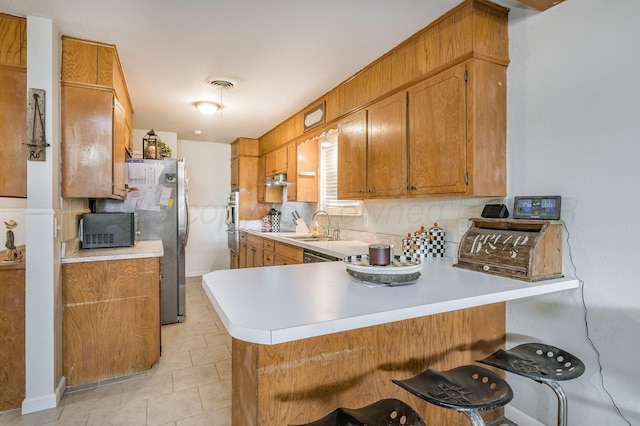 kitchen with visible vents, backsplash, light countertops, a peninsula, and a sink