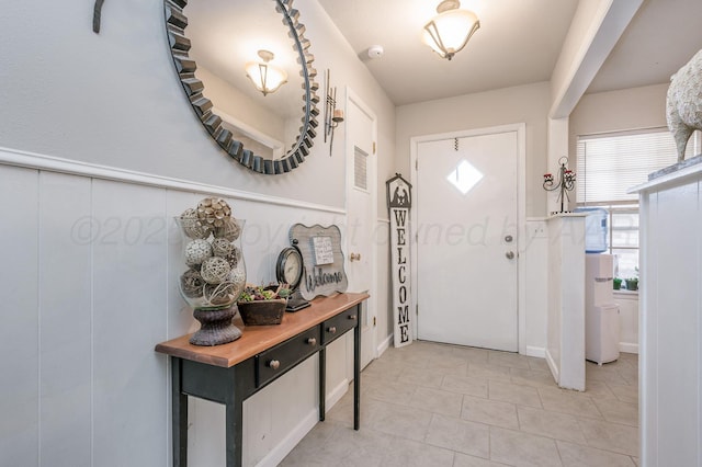 foyer entrance with visible vents, a wainscoted wall, and light tile patterned flooring