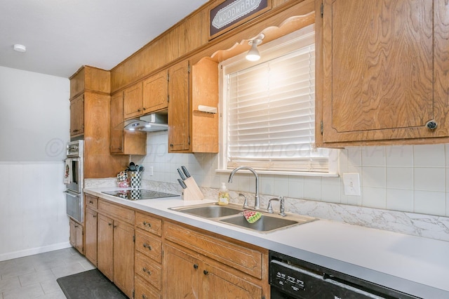 kitchen featuring under cabinet range hood, light countertops, black appliances, a warming drawer, and a sink