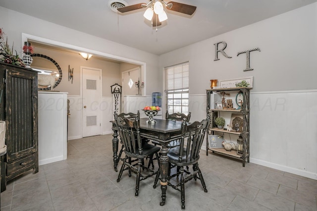 tiled dining room with visible vents, wainscoting, and ceiling fan