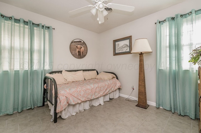 bedroom featuring baseboards, multiple windows, light tile patterned flooring, and a ceiling fan