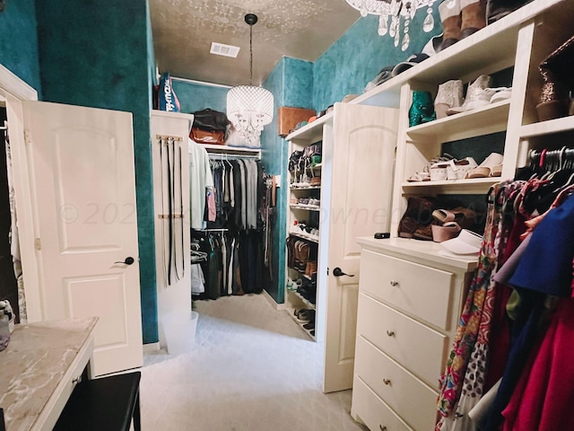 spacious closet featuring a notable chandelier and light carpet