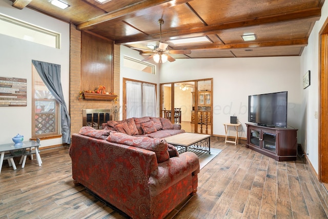 living room featuring a brick fireplace, ceiling fan, dark hardwood / wood-style flooring, and lofted ceiling with beams