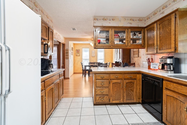 kitchen with light tile patterned flooring, white fridge, a textured ceiling, black dishwasher, and kitchen peninsula