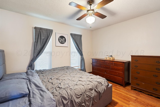 bedroom with ceiling fan, a textured ceiling, and light hardwood / wood-style flooring