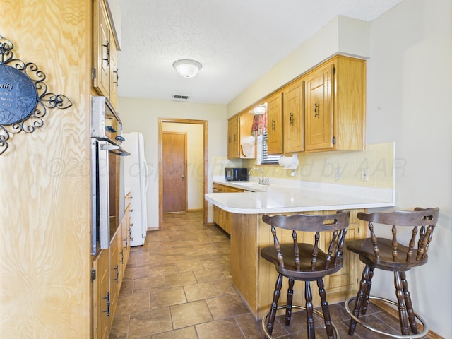1620 N Nelson St, Pampa, TX 79065 - kitchen with a peninsula, a kitchen bar, light countertops, tasteful backsplash, and a textured ceiling