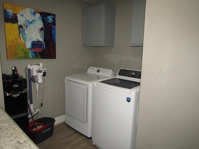 clothes washing area with cabinets, washing machine and dryer, and dark hardwood / wood-style flooring