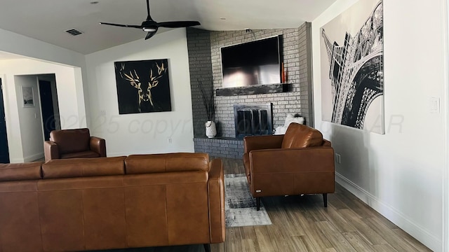 living room with a brick fireplace, vaulted ceiling, hardwood / wood-style floors, and ceiling fan