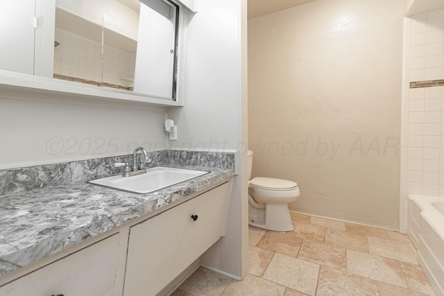 full bath with toilet, stone finish floor, and vanity