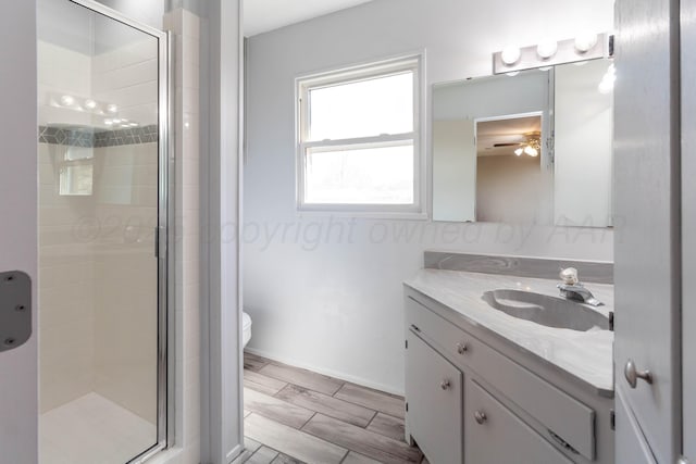 full bathroom featuring toilet, ceiling fan, a stall shower, and vanity