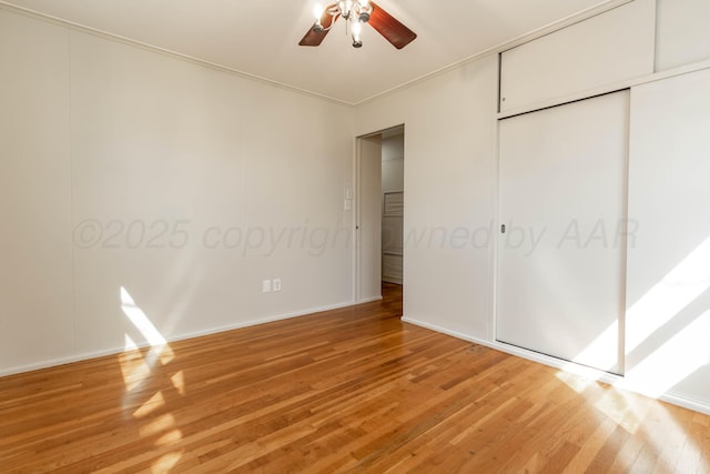unfurnished bedroom featuring a closet, light wood finished floors, baseboards, and a ceiling fan
