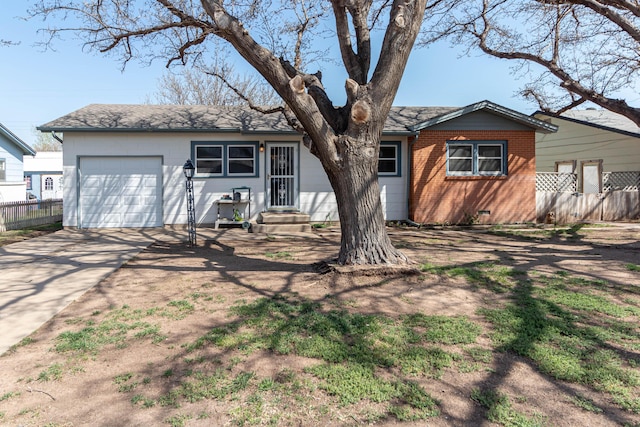 rear view of house with a garage, entry steps, roof with shingles, fence, and driveway