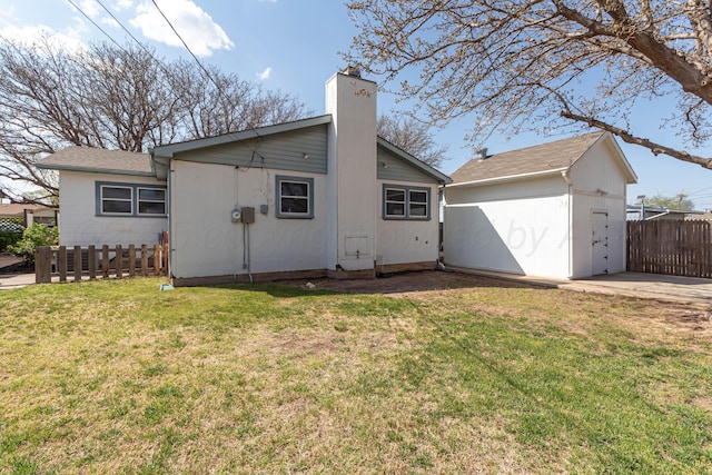 rear view of property with a yard, a chimney, fence, an outdoor structure, and a storage unit