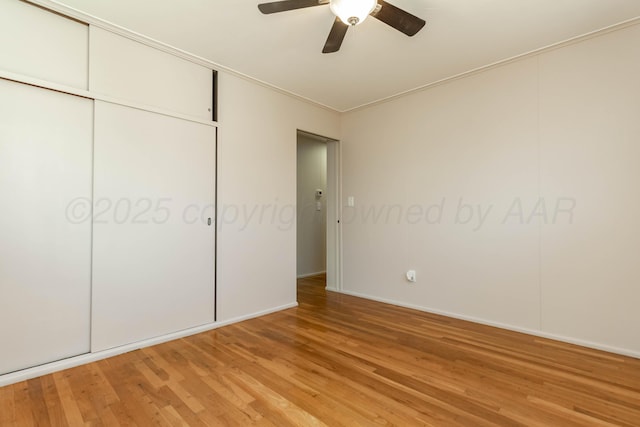 unfurnished bedroom featuring a closet, baseboards, light wood-type flooring, and a ceiling fan