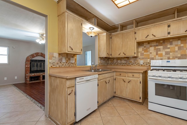 kitchen featuring tasteful backsplash, white appliances, light tile patterned floors, light countertops, and a sink