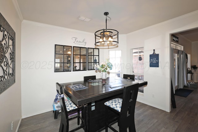 dining space with crown molding, visible vents, wood finished floors, and a chandelier