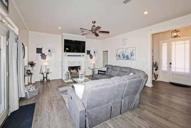 living area with a ceiling fan, wood finished floors, ornamental molding, recessed lighting, and a premium fireplace