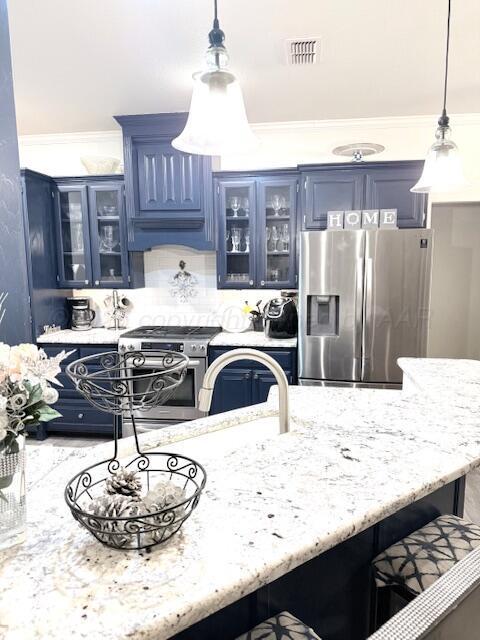 kitchen with pendant lighting, appliances with stainless steel finishes, a kitchen breakfast bar, and blue cabinetry