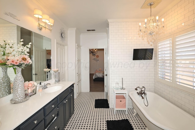 ensuite bathroom with visible vents, crown molding, vanity, a chandelier, and a soaking tub