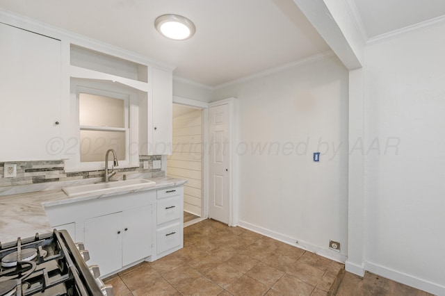 kitchen with white cabinetry, crown molding, gas range, decorative backsplash, and a sink