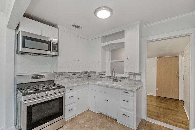 kitchen with visible vents, a sink, ornamental molding, appliances with stainless steel finishes, and decorative backsplash