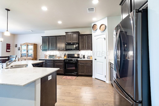 1006 Pinot Blvd, Amarillo, TX 79124 - kitchen with black appliances, light wood-style flooring, dark brown cabinets, recessed lighting, and decorative light fixtures