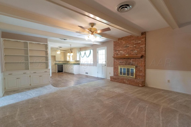 4903 Princeton St, Amarillo, TX 79109 - unfurnished living room featuring light colored carpet, beam ceiling, a ceiling fan, a brick fireplace, and wainscoting