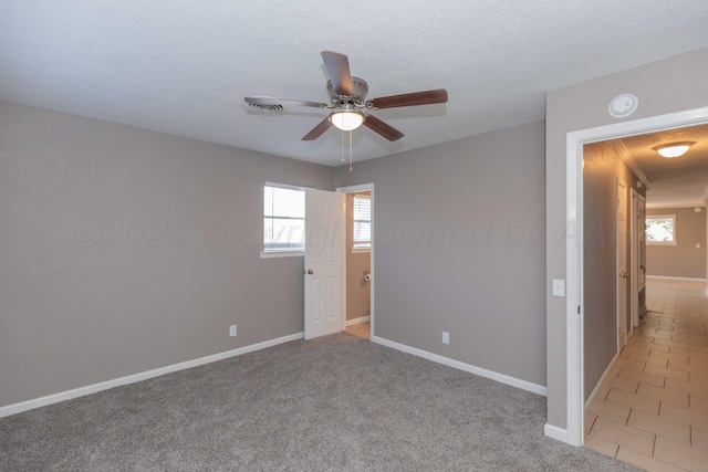 carpeted spare room featuring a textured ceiling and ceiling fan