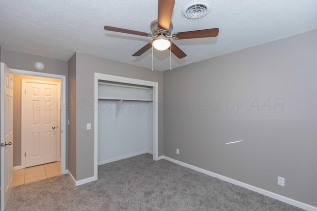 unfurnished bedroom with a textured ceiling, ceiling fan, light carpet, and a closet