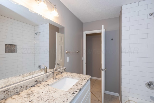 bathroom with tile patterned flooring, vanity, a textured ceiling, and tiled shower / bath combo