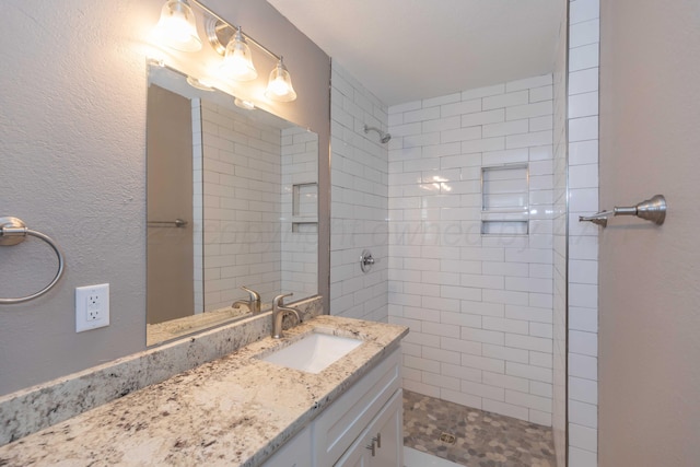 bathroom featuring a tile shower and vanity