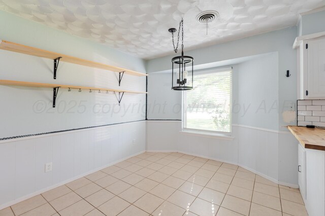 5210 S Milam St, Amarillo, TX 79110 - unfurnished dining area with a wainscoted wall and light tile patterned flooring