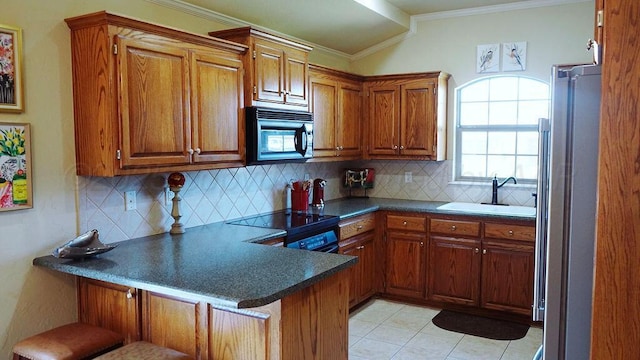 kitchen with a sink, brown cabinets, black microwave, electric range oven, and a peninsula